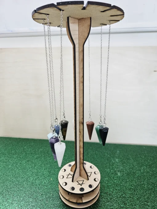 Close-up of wooden pendulum stand base engraved with moon phases and elemental symbols.