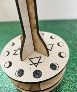 Close-up of wooden pendulum stand base engraved with moon phases and elemental symbols.