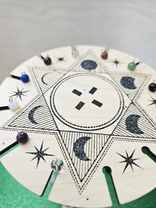 Top view of laser-engraved pendulum stand featuring celestial design and hanging crystals.