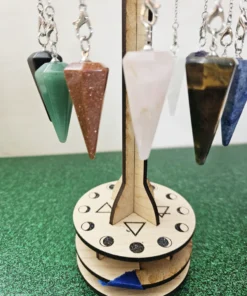 Assorted gemstone pendulums hanging on a wooden sacred geometry display stand.