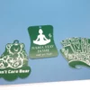 Three green weed-themed keychains featuring humorous designs including “I Don’t Care Bear,” “Nama Stay Home and Get High,” and “We’re All Mad 4/20 Here.”
