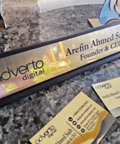 Personalized gold desk name plate with company logo and CEO title, displayed on granite surface with matching cards.