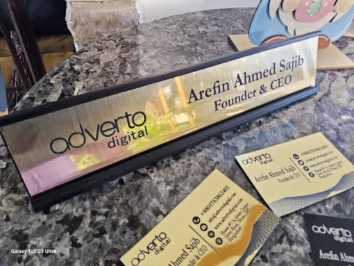 Personalized gold desk name plate with company logo and CEO title, displayed on granite surface with matching cards.