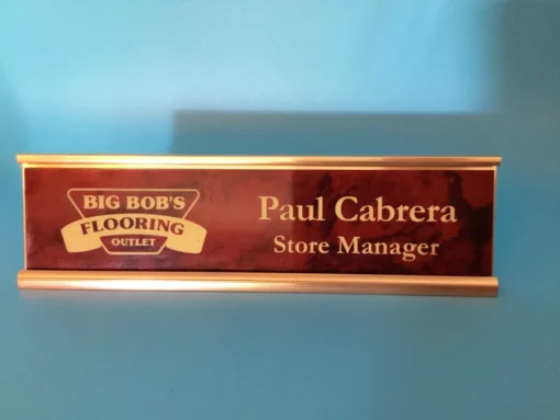 Engraved red marbled and gold desk name plate with custom text and sleek holder, ideal for office or professional use.