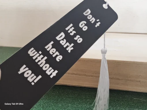 Black inspirational bookmark with white tassel – “Don’t go, it’s so dark here without you!”