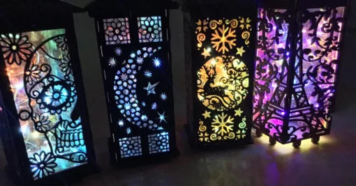 Colorful LED lanterns with intricate cutout designs – sugar skull, crescent moon, reindeer, and Eiffel Tower.